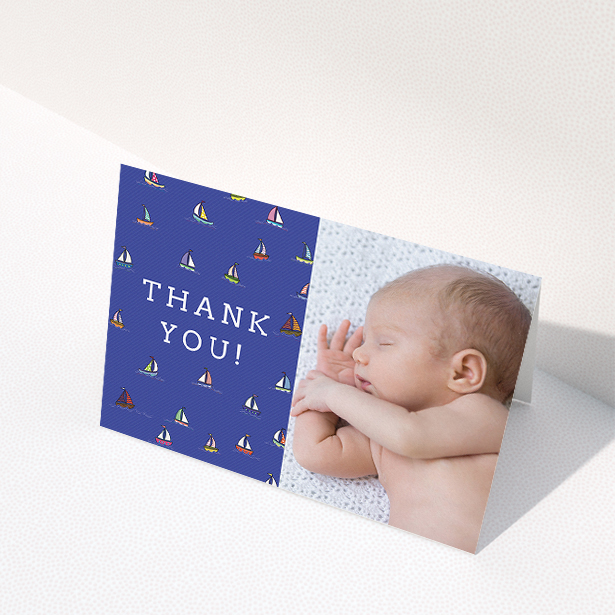 A baby thank you card template titled "Cowes Week". It is an A5 card in a landscape orientation. It is a photographic baby thank you card with room for 1 photo. "Cowes Week" is available as a folded card, with mainly blue colouring.