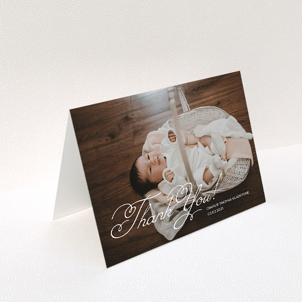 A baby thank you card called "Flourished Thank You". It is an A5 card in a landscape orientation. It is a photographic baby thank you card with room for 1 photo. "Flourished Thank You" is available as a folded card, with mainly white colouring.