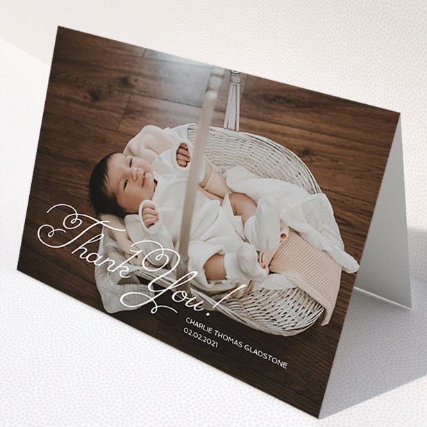 A baby thank you card called "Flourished Thank You". It is an A5 card in a landscape orientation. It is a photographic baby thank you card with room for 1 photo. "Flourished Thank You" is available as a folded card, with mainly white colouring.