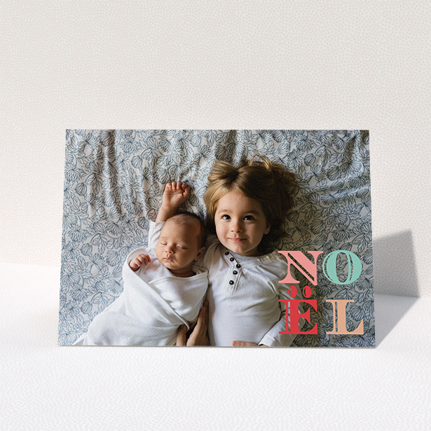 A custom christmas card design named "Pastel Noel". It is an A5 card in a landscape orientation. It is a photographic custom christmas card with room for 1 photo. "Pastel Noel" is available as a folded card, with mainly pink colouring.