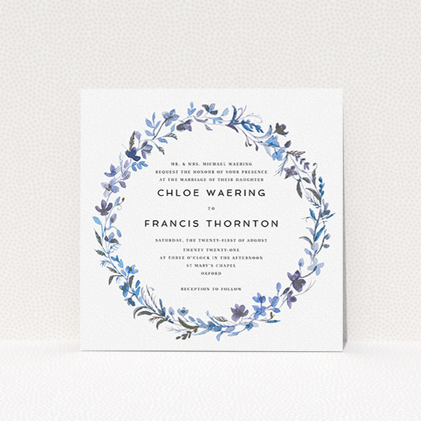 A personalised wedding invite design titled "Blue Floral Wreath". It is a square (148mm x 148mm) invite in a square orientation. "Blue Floral Wreath" is available as a flat invite, with tones of light blue, purple and grey.