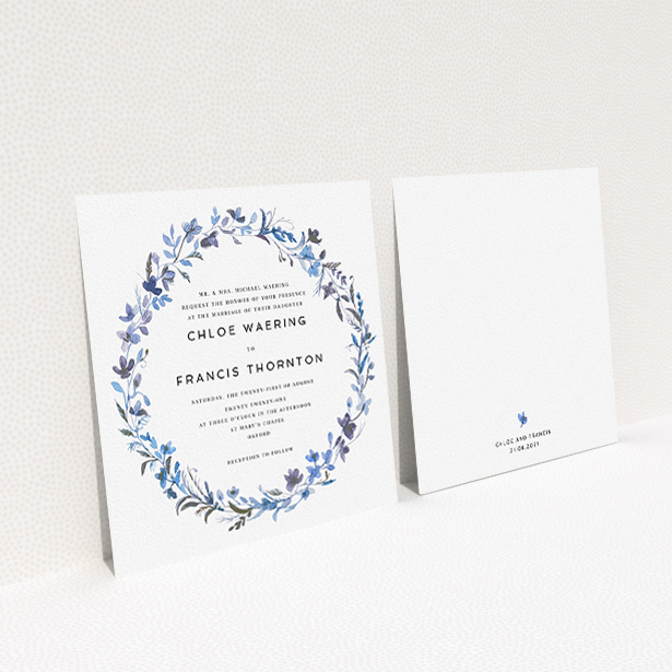 A personalised wedding invite design titled "Blue Floral Wreath". It is a square (148mm x 148mm) invite in a square orientation. "Blue Floral Wreath" is available as a flat invite, with tones of light blue, purple and grey.