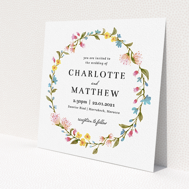 A personalised wedding invite template titled "Spring Wreath". It is a square (148mm x 148mm) invite in a square orientation. "Spring Wreath" is available as a flat invite, with mainly pink colouring.