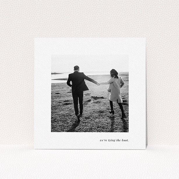 A wedding invite card named "Knot Tying". It is a square (148mm x 148mm) invite in a square orientation. It is a photographic wedding invite card with room for 1 photo. "Knot Tying" is available as a flat invite, with mainly white colouring.