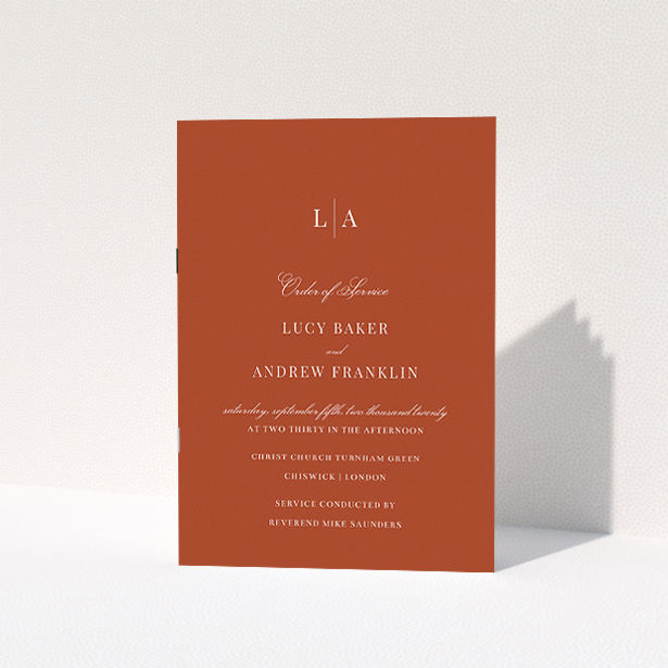 A wedding order of service named "Dark Ochre Monogrammed". It is an A5 booklet in a portrait orientation. "Dark Ochre Monogrammed" is available as a folded booklet booklet, with mainly dark orange colouring.