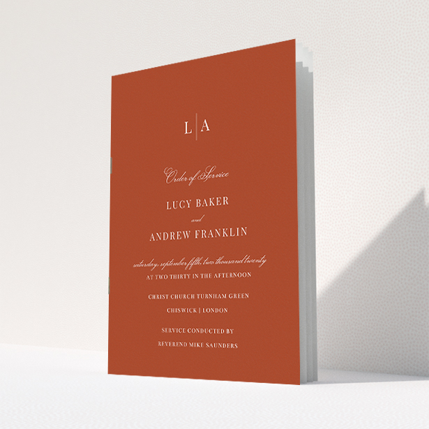 A wedding order of service named "Dark Ochre Monogrammed". It is an A5 booklet in a portrait orientation. "Dark Ochre Monogrammed" is available as a folded booklet booklet, with mainly dark orange colouring.