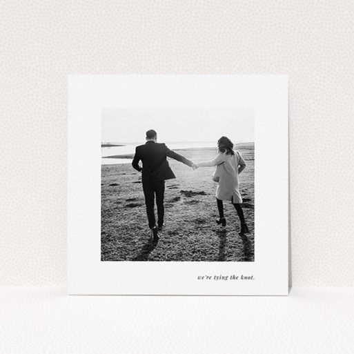 Wedding Save The Date Card Design - "Knot Tying" A wedding save the date card template titled "Knot Tying". It is a square (148mm x 148mm) card in a square orientation. It is a photographic wedding save the date card with room for 1 photo. "Knot Tying" is available as a flat card, with mainly white colouring.