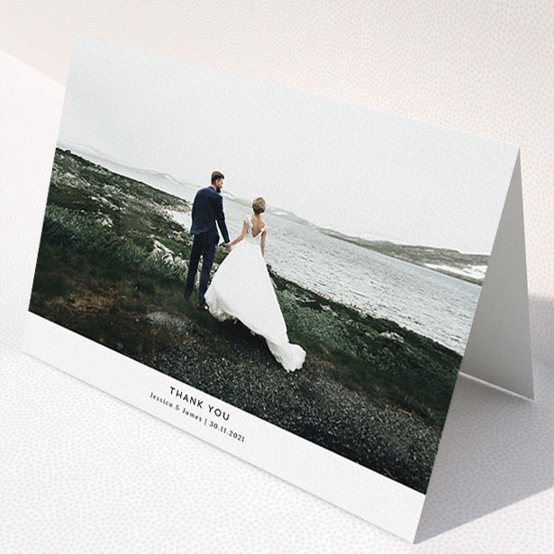 A wedding thank you card named "Sans Serif". It is an A5 card in a landscape orientation. It is a photographic wedding thank you card with room for 1 photo. "Sans Serif" is available as a folded card, with mainly white colouring.
